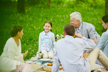 Happy little girl looking at her grandmother during talk at family picnic