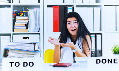 Young female office worker shocked by the huge amount of paper work. Deadline concepts.