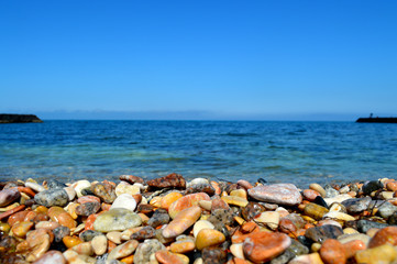 beach with colorful pebbles. at sea there is a calm, and in the sky neither clouds