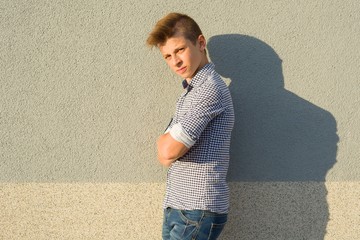 Outdoor portrait of teenage boy 14, 15 years old. Gray wall background, copy space.