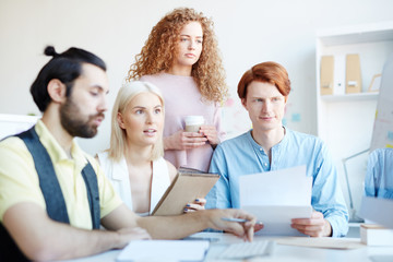 Young designers in casualwear discussing online data while preparing new project and looking for new information