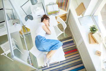 Young manager in casualwear sleeping right on her desk in open space office