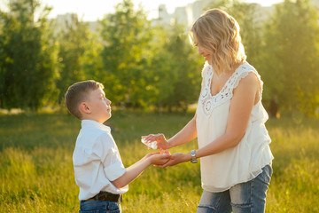 beautiful and young blonde mom taking care and applying antiseptic antibacterial gel on the son's hand