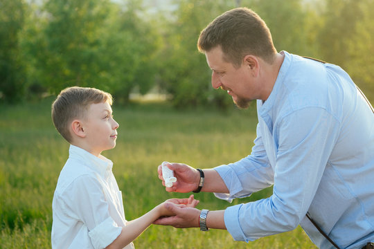 bearded father taking care and applying antiseptic antibacterial gel on the son's hand