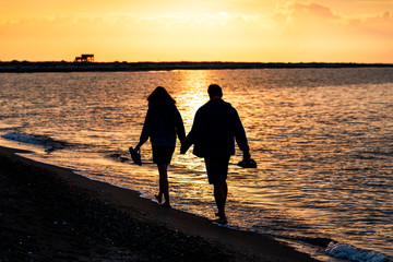 couple in love walking on the beach in the sunset, holding hands