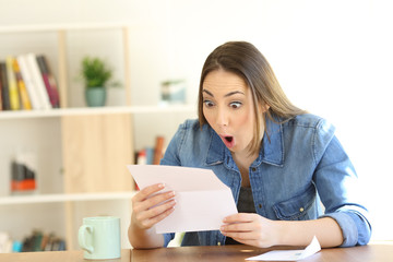 Amazed woman reading surprising news in a letter