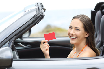 Driver showing a blank credit card in a cabriolet car