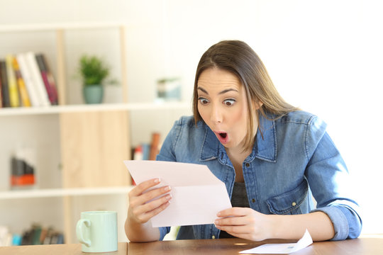 Amazed woman reading surprising news in a letter