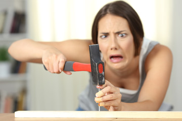 Woman hitting finger with a hammer