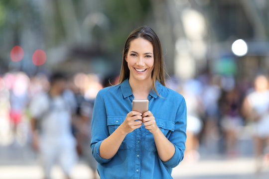 Woman holding smart phone looks at camera