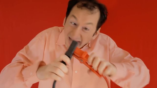 A funny ugly man carelessly connecting two electrical wires and receiving a harmful shock (electrocuted). Comedy shot. Version without effect graphics.
