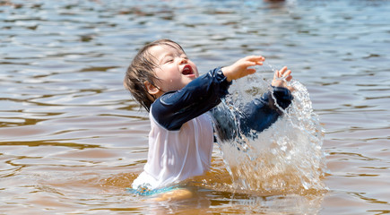 Toddler boy swimming in a big lake on a summer day