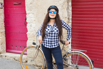 Beautiful young woman with bicycle and helmet in street on sunny day