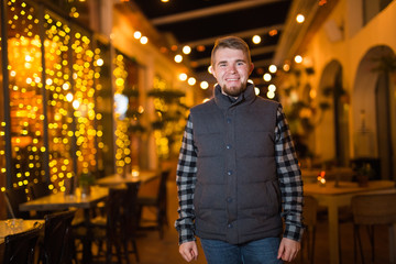 Young happy man looking at camera in the night cafe
