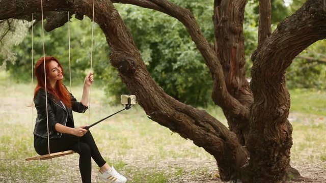 Redhead girl straightens her hair and taking a photo with a self monopod