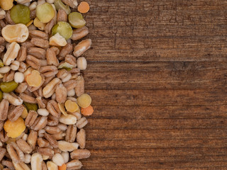 Assorted grains and pulses mix on wooden background, with copy space. Winter food includes split peas, red and yellow lentils, pearl barley, kamut, spelt.