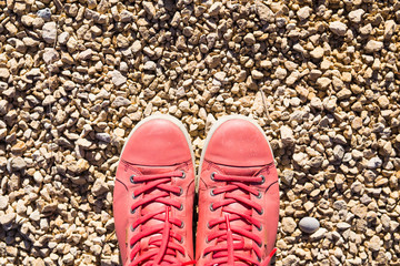 Red sneakers on dry ground. On the paving stones are red sneakers