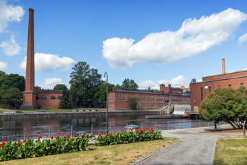Old red brick industrial buildings and park along the Tammerkoski rapids in downtown Tampere, Finland on a sunny day in the summer. © tuomaslehtinen