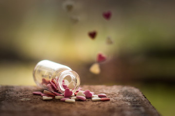 Small, colorful bunch of hearts in a jar, lying on a wooden table. Shallow depth of field, soft effect.