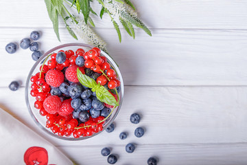 Blueberries, raspberries and red currant in a bowl on a wooden background. Top view, free space