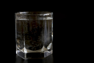 Glass with clear water on a black background
