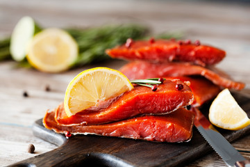Smoked salmon fillet with pepper, salt, rosemary and lemon and rosemary on wooden table