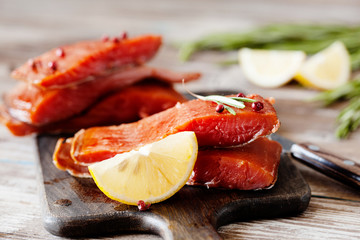 Smoked salmon fillet with pepper, salt, rosemary and lemon and rosemary on wooden table