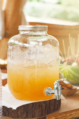Lemonade fresh lemon sliced in glass jar with tap on wooden stand outdoors. Ice cold useful juicy beverage in hot weather Refreshing drink. Summer time