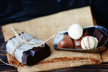 Heap of broken pieces of chocolate on wooden background. Delicious chocolate candies in gift box on table close-up.