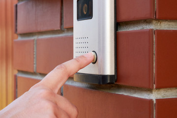 The female hand presses a button doorbell with intercom
