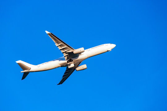Passenger plane flying in the blue sky in sunlight rays