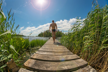 Sexy young man walks along a jetty at beautiful summer weather © DZiegler