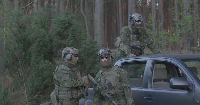 Special forces soldiers in a full combat uniform on a post in the woods