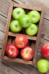 Green and red apples in wooden box