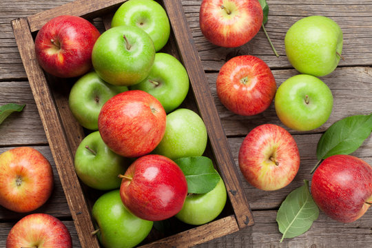 Green and red apples in wooden box