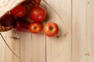 Ripe red apples in a basket on a bright wooden background. Top view
