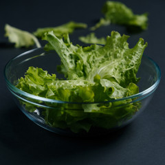 fresh salad leaves in bowl on dark background. Top view