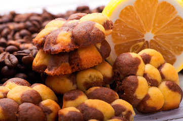 Unusual cute cookies with lemon and coffee close-up. Sweet pastries in the form of flowers. Dessert with citrus taste. Grains of coffee for decoration in the background.