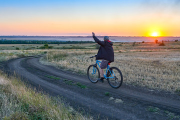 Fototapeta premium man ride a bike in the country on the field in the evening