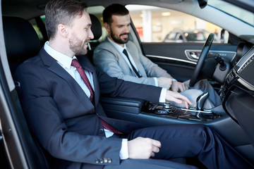 Smiling salesperson sitting with client in salon of a new car