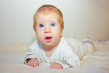 A baby with blue eyes looks up. A sweet baby lies on his stomach and learns to hold his head....