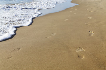 Fototapeta na wymiar FOOT STEPS PRINTED ON WET SEA SAND BEACH