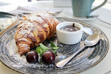 French croissant with almonds, cherries and chocolate sauce