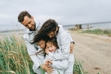Beautiful family portrait dressed in raincoat near the lake