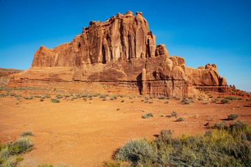 Fototapeta premium The deep red slickrock formations found along the roadside in Arches National Park are striking against an electric blue sky