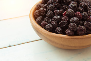 Ripe fresh blackberries in a wooden bowl on the table