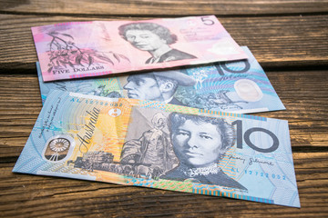 Several banknotes of Australian dollars on the aged wooden surface, close up.