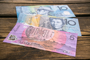 Several banknotes of Australian dollars on the aged wooden surface, close up.