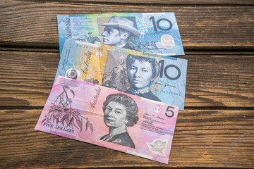 Several banknotes of Australian dollars on the aged wooden surface, close up.