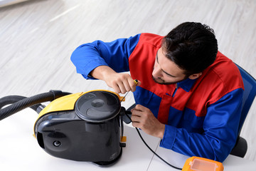 Man repairman repairing vacuum cleaner at service center